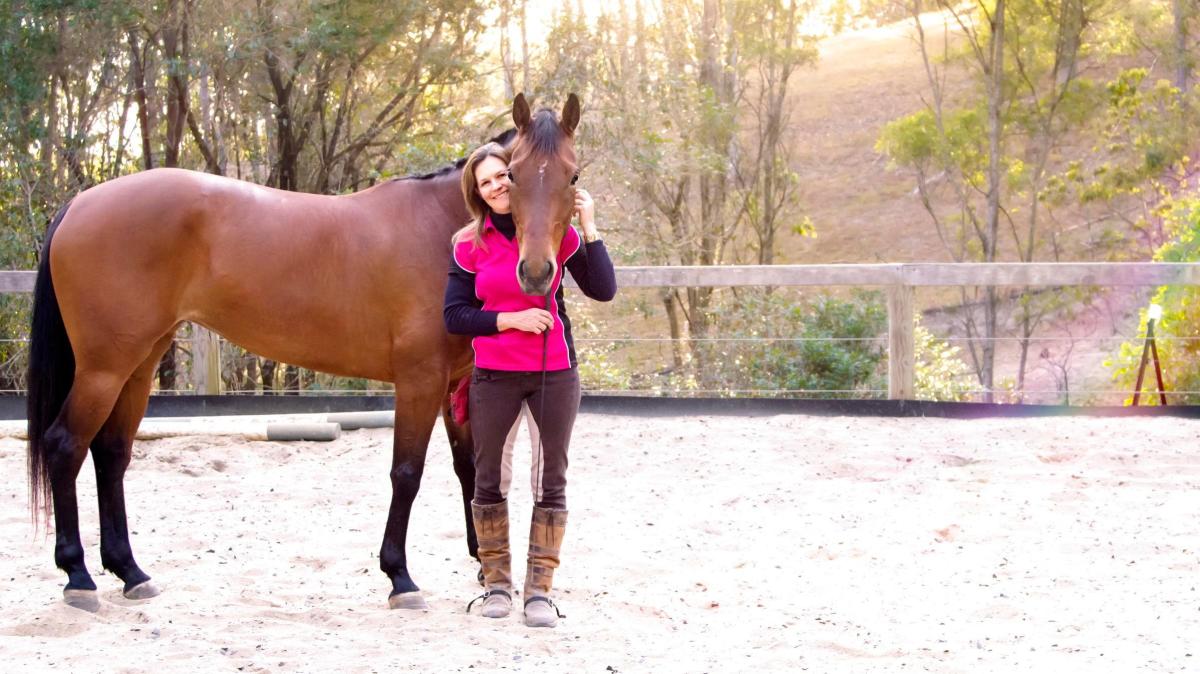 Debbie Burgermeister, Head Coach a woman holding a brown horse standing next to a fence