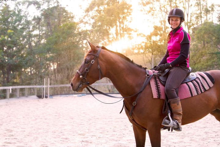 a woman riding on the back of a brown horse