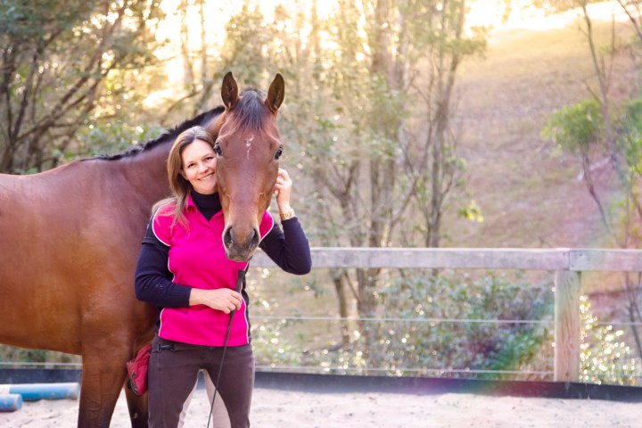 a woman standing next to a horse
