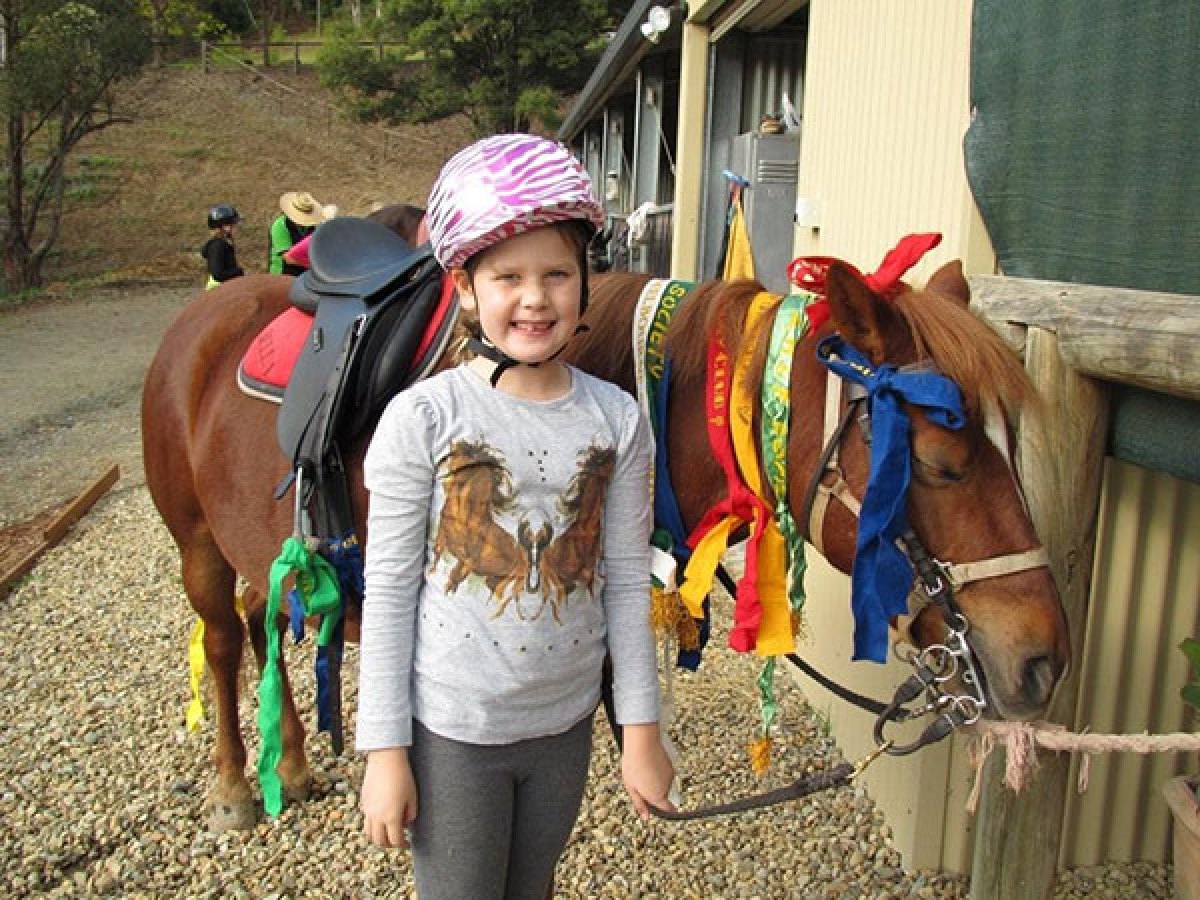 a little girl riding on the back of a horse